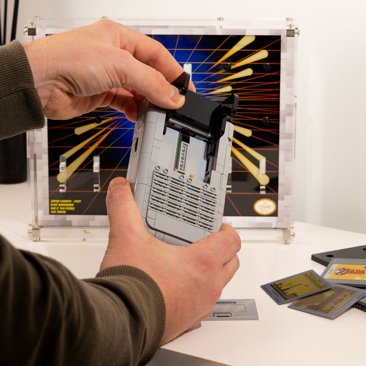 Hands fitting the LEGO Game Boy onto the clear hooks