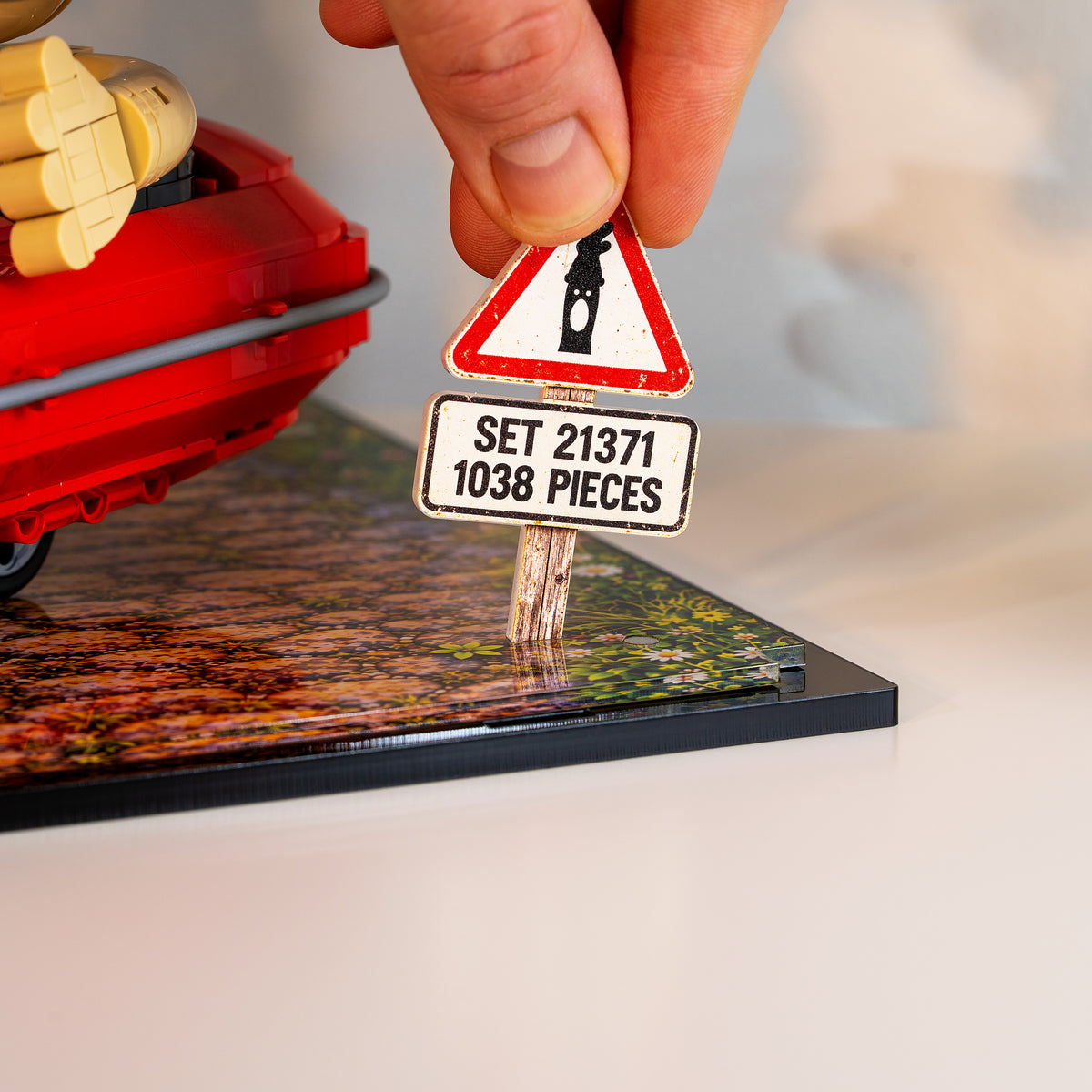 A hand placing the set 21371 sign into the base of the case